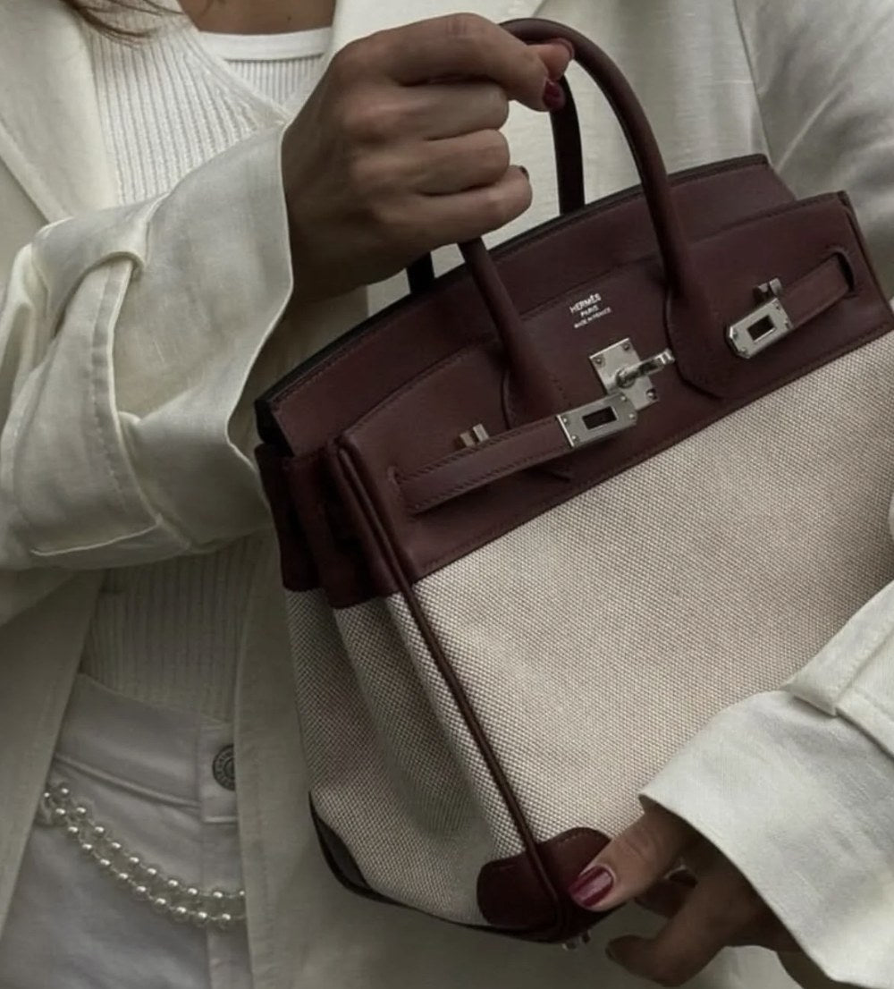 Hermès Birkin in toile and burgundy leather held by a woman in a white suit